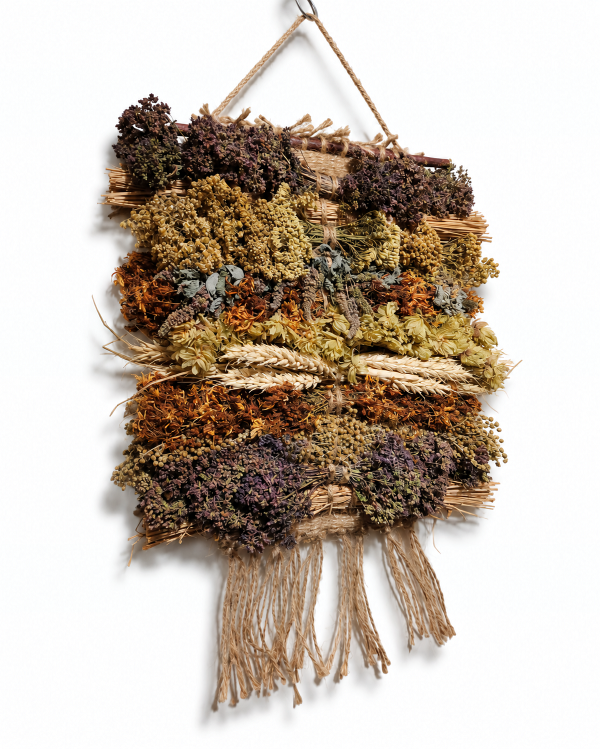 Frontal view of a 20x30cm handcrafted dried flower and wild herb wall hanging tapestry with jute fringe.
