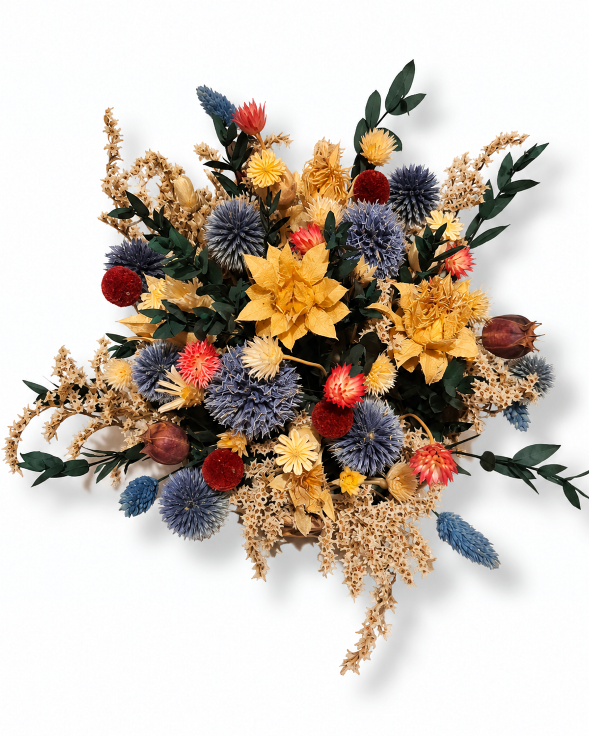 Top-down view of a colorful dried flower basket with blue echinops, yellow cephalaria, and preserved greenery.
