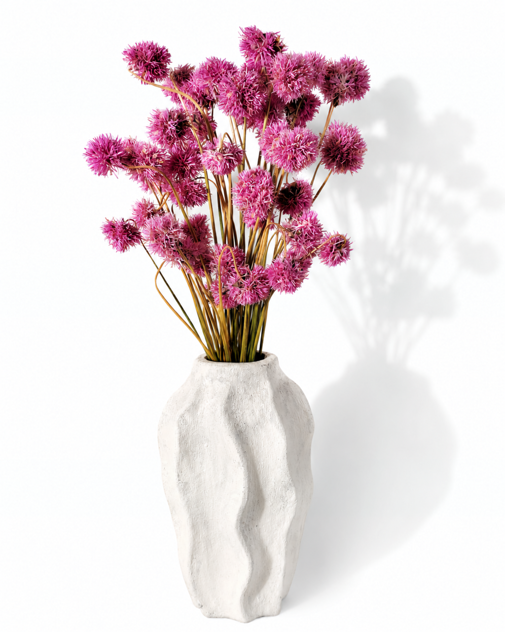 Full bouquet of vibrant pink dried Gomphrena globe flowers displayed in a white ceramic vase.

