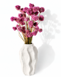 Full bouquet of vibrant pink dried Gomphrena globe flowers displayed in a white ceramic vase.

