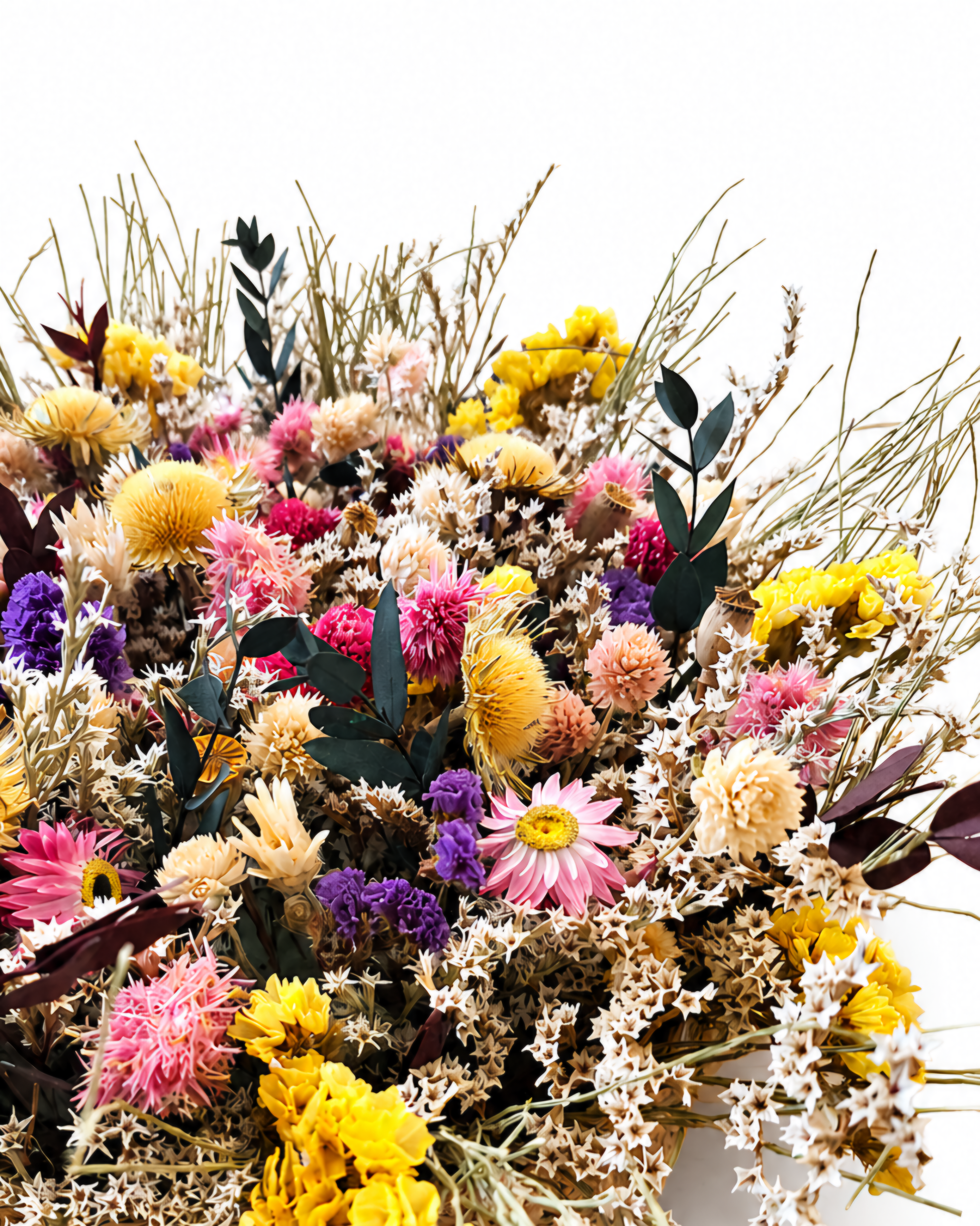Macro detailed shot of pink, yellow, purple, and white dried wildflower blooms and botanical textures.
