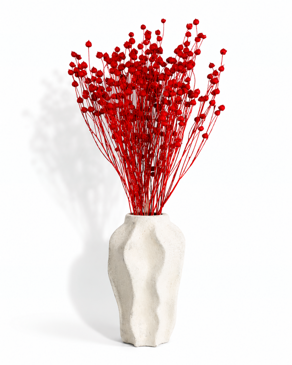 A beautiful aesthetic arrangement of vibrant red preserved flax stems in a modern textured white vase
