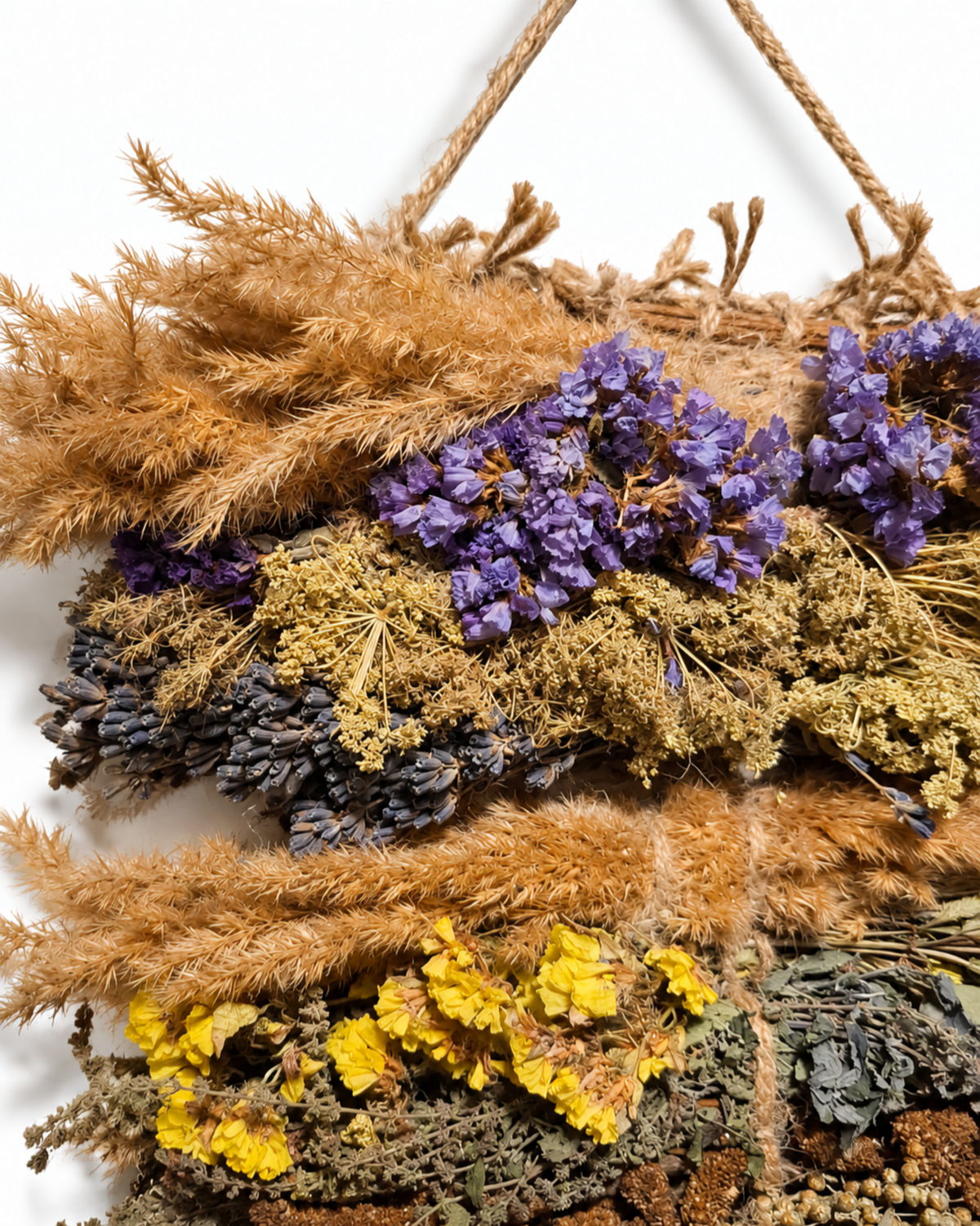 Close-up of top layers of purple statice, dried lavender, and wild grasses on a woven tapestry.
