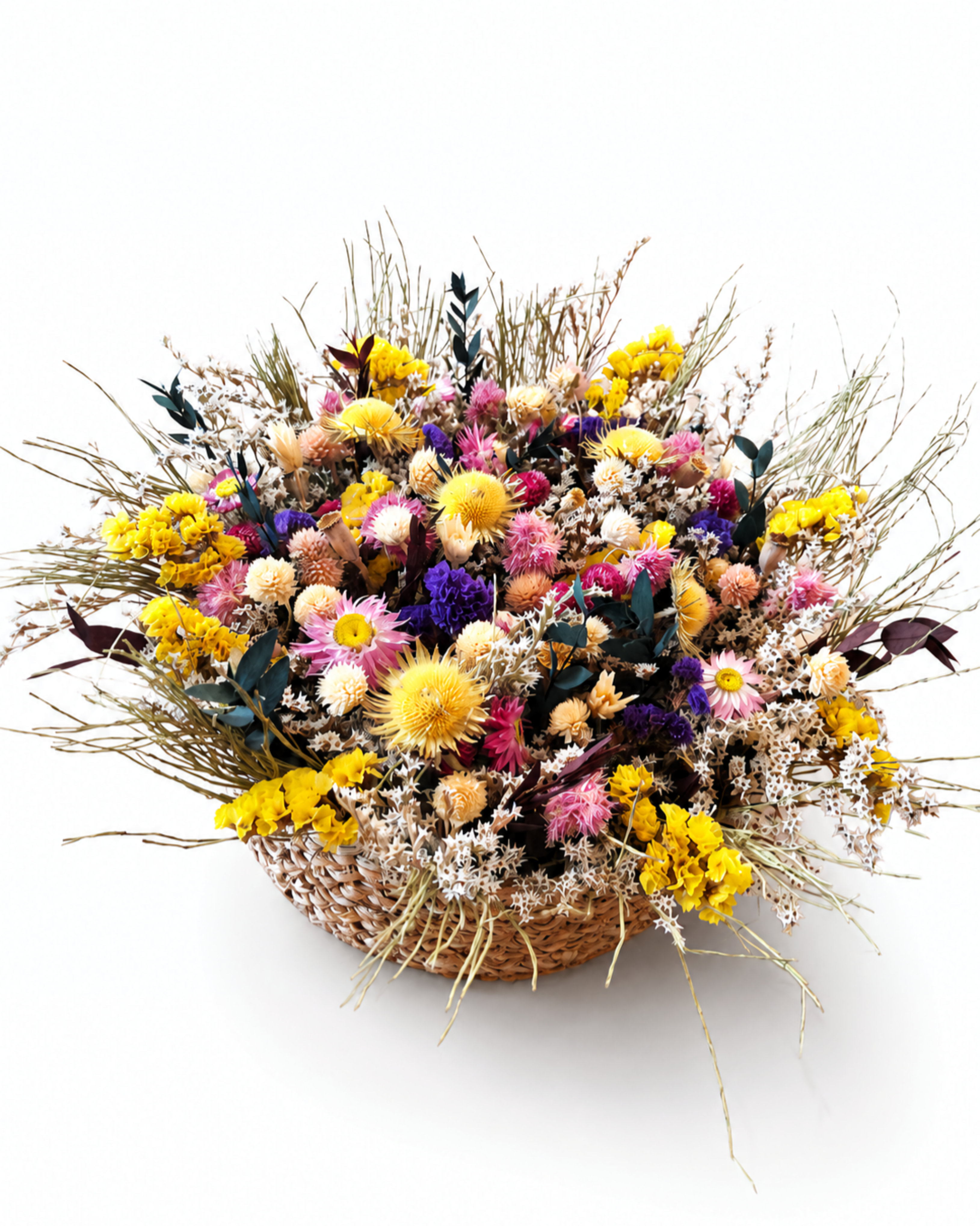 Full view of a hand-woven straw basket arrangement filled with vibrant dried wildflowers isolated on white.
